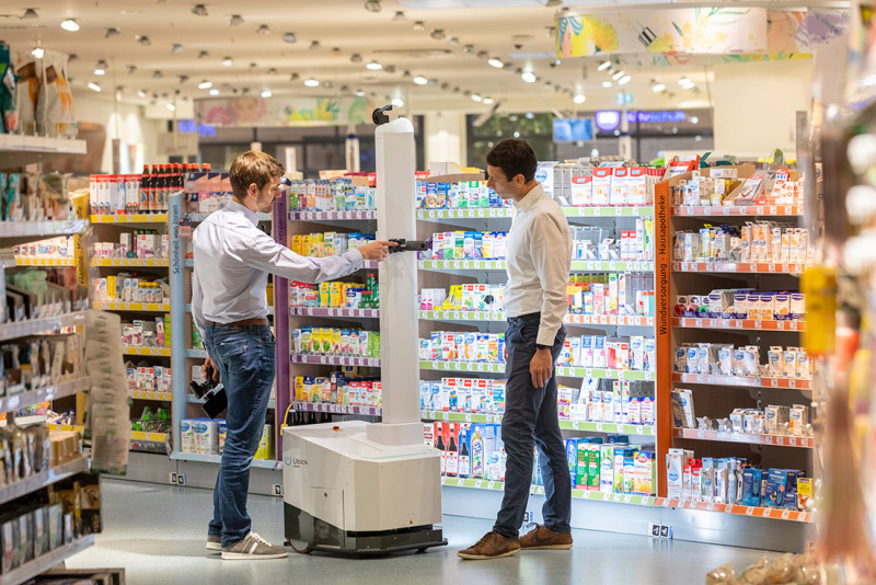 The managing directors of Ubica Robotics Georg Bartels (l.) and Jonas Reiling demonstrate their scanning robot in a branch of a drugstore chain in Bremen. 