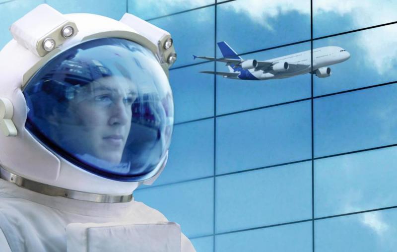 Mann mit Raumfahrthelm und Spiegelung eines Flugzeugs in einer gläsernen Wand.
