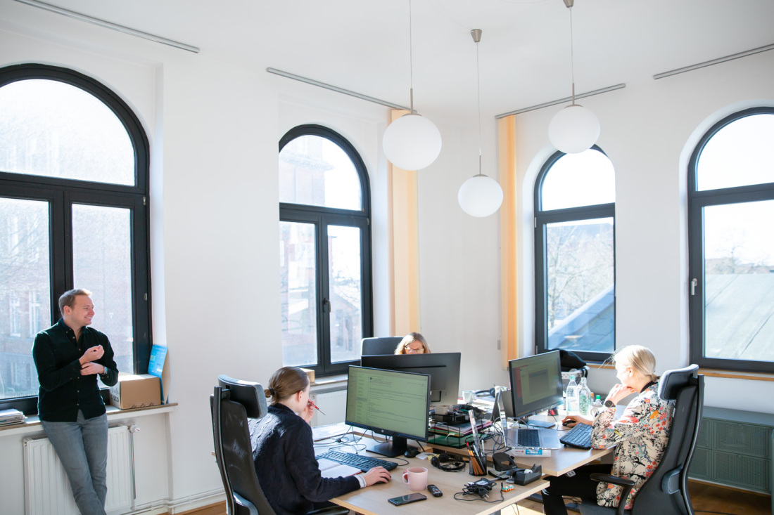 Vier Personen sitzen an Computern in einem Büro und arbeiten