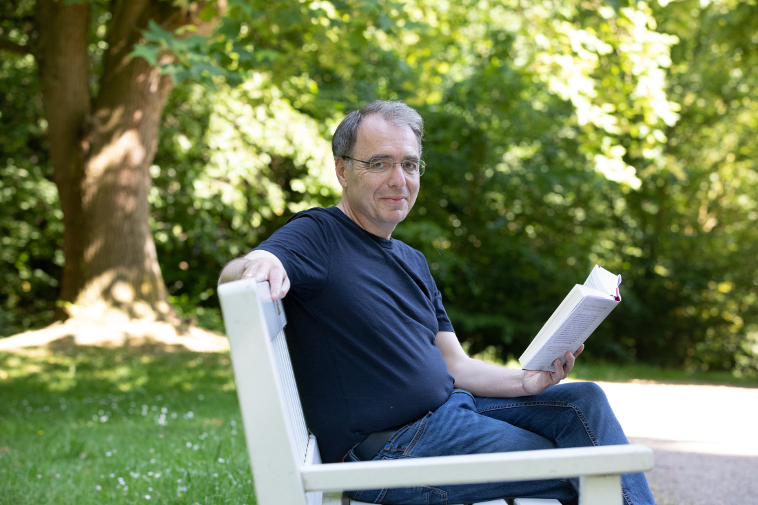 David Safier sitzt mit einem Buch auf einer Bank