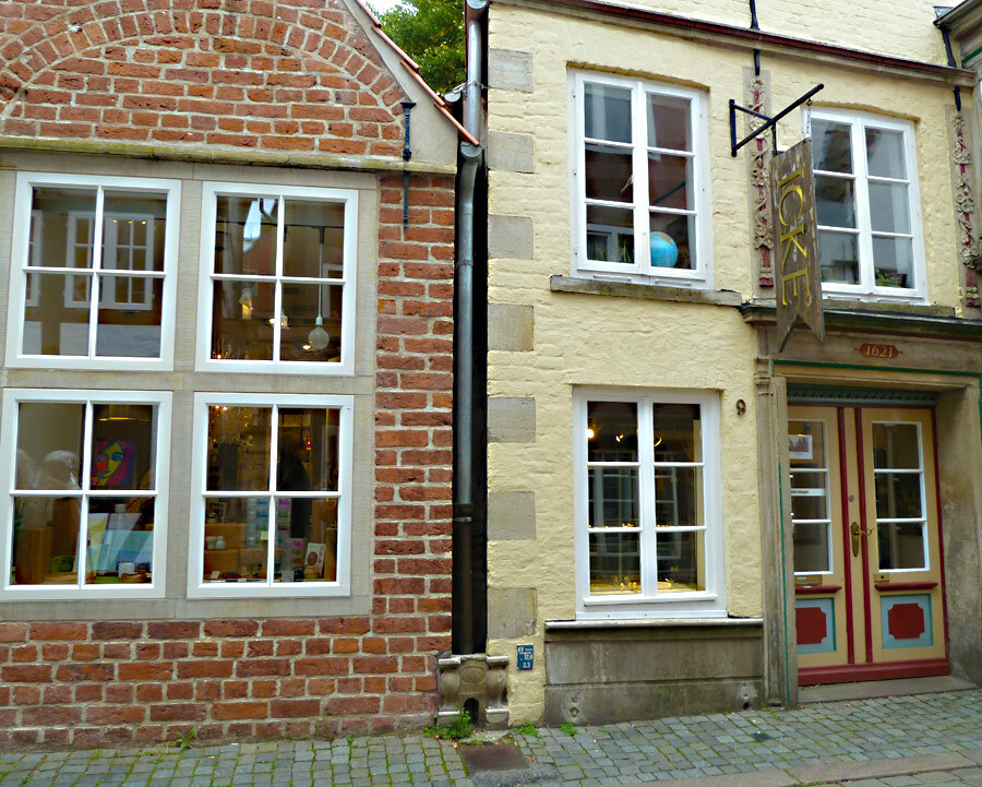 Zwei kleine alte Häuser im historischen Bremer Schnoor, zwischen ihnen ist ein liebevoll gestalteter Durchgang für Katzen in die Mauer eingelassen.
