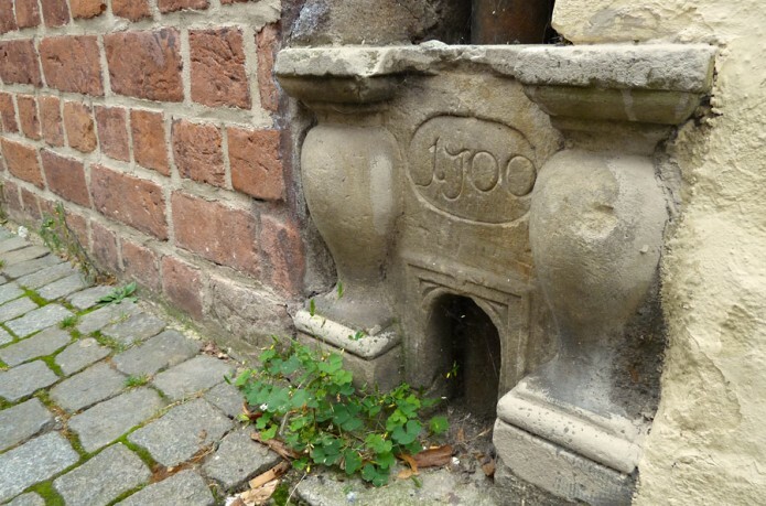 Ein kleiner Eingang für eine Katze in einer Hausmauer im historischen Bremer Schnoor. Der Durchganz ist verziert mit Säulen und Gravur.